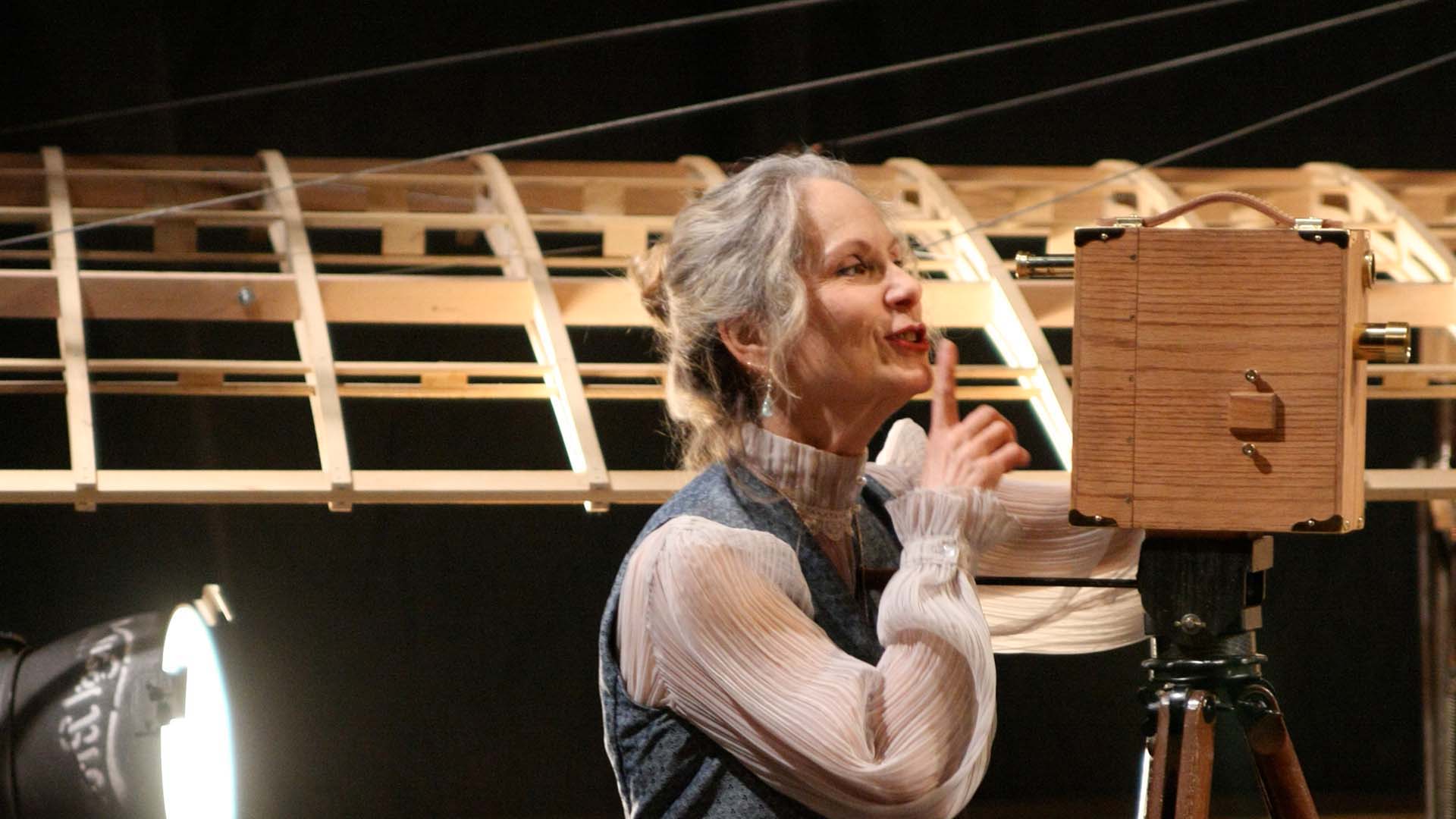 Woman on stage giving a shush gesture