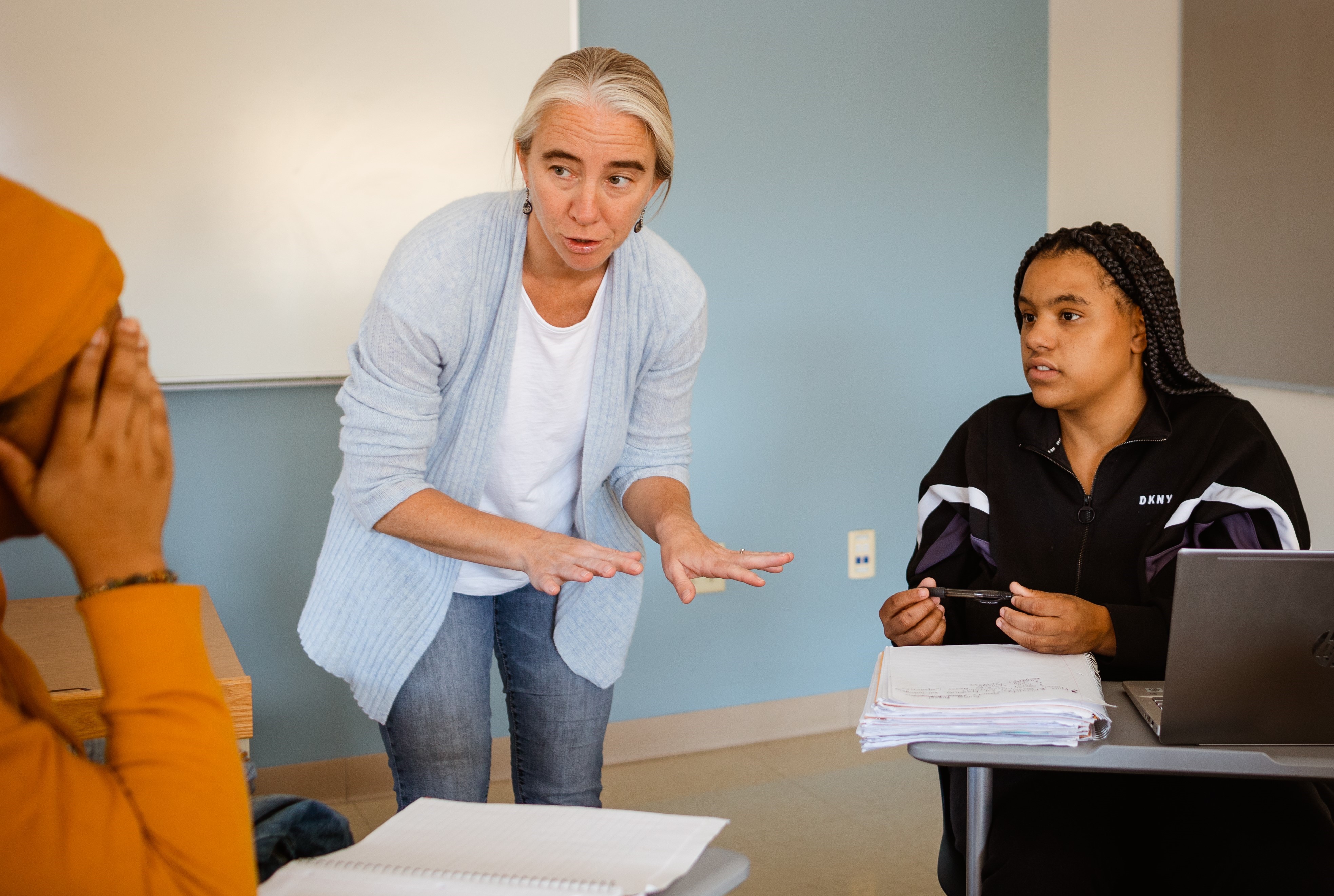 Professor speaking with two students in the classroom